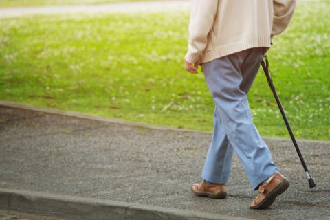 Man walking in neighborhood with cane